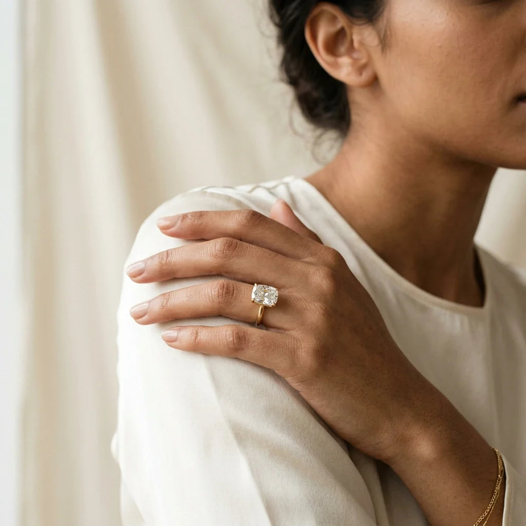 Elongated cushion-cut diamond solitaire ring on a polished 18k yellow gold band on a white studio background