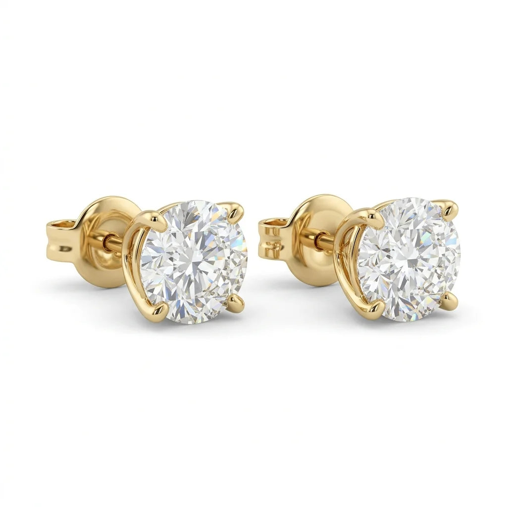 Pair of round brilliant diamond stud earrings in 18k yellow gold martini settings on a white studio background