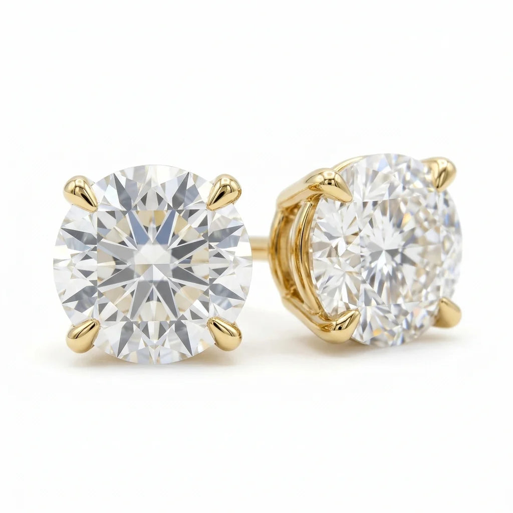 Pair of round brilliant diamond stud earrings in 18k yellow gold martini settings on a white studio background