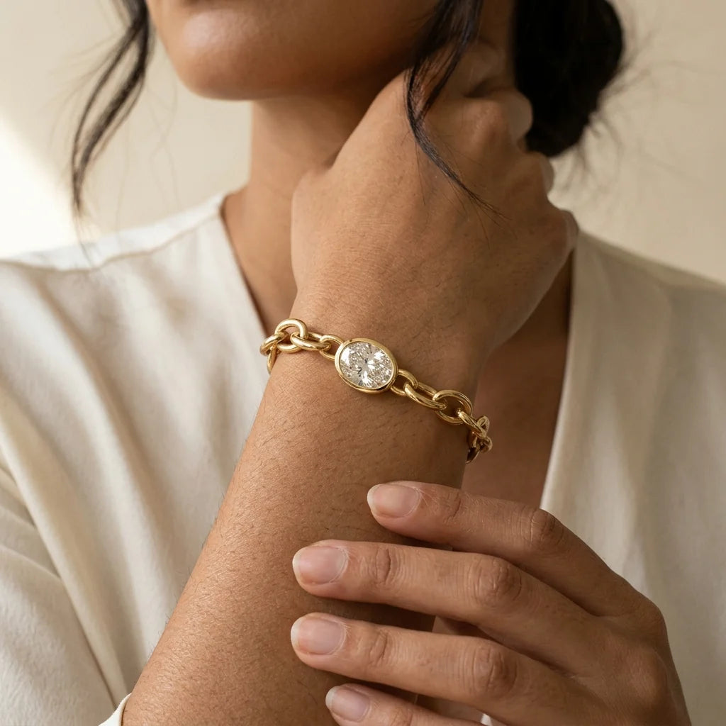 Sculpted 18k yellow gold link bracelet with a bezel-set oval diamond station on a white studio background