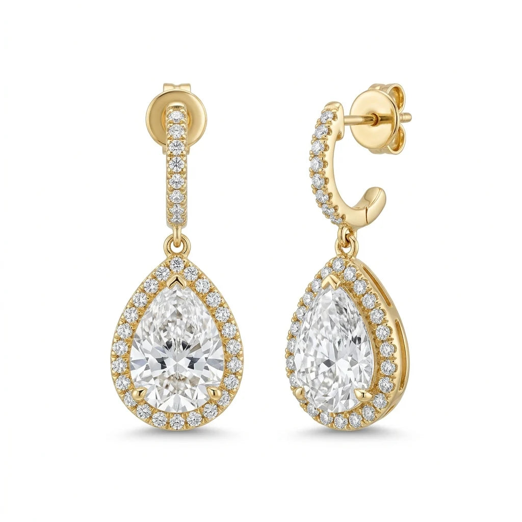 Pair of pear-shaped diamond drop earrings with pavé halos in 18k yellow gold on a white studio background
