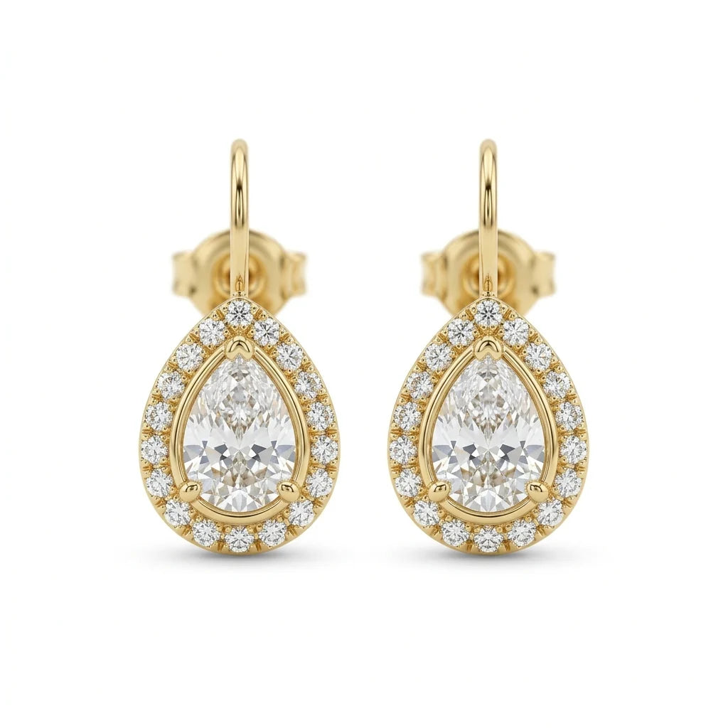 Pair of pear-shaped diamond drop earrings with pavé halos in 18k yellow gold on a white studio background