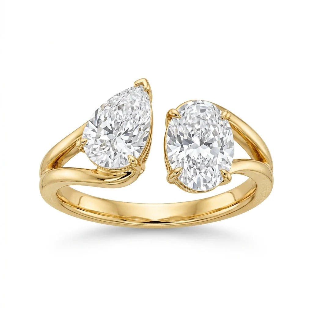 Toi et moi ring with a pear-cut and an oval-cut diamond facing each other on an 18k yellow gold band, white studio background
